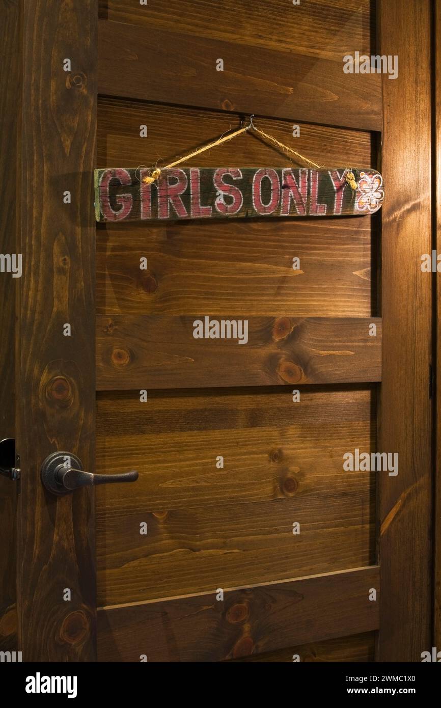 Las niñas pintadas de rojo solo notan la señal en la puerta de madera marrón del dormitorio dentro de la lujosa casa escandinava de madera y troncos. Foto de stock