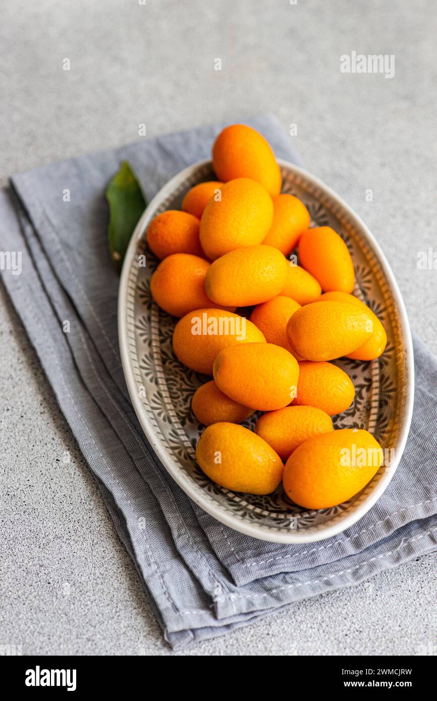 Vista de arriba de kumquats maduros en un tazón en una servilleta doblada Foto de stock