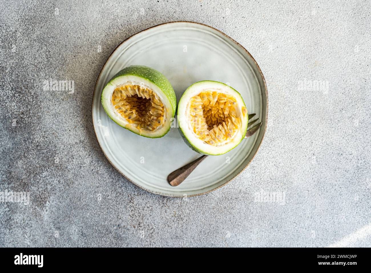 Vista aérea de una fruta de la pasión reducida a la mitad en un plato Foto de stock