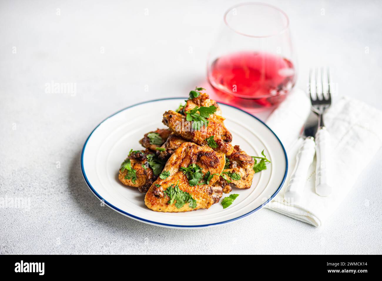 Primer plano de alitas de pollo asadas con cilantro y una bebida de frutas Foto de stock