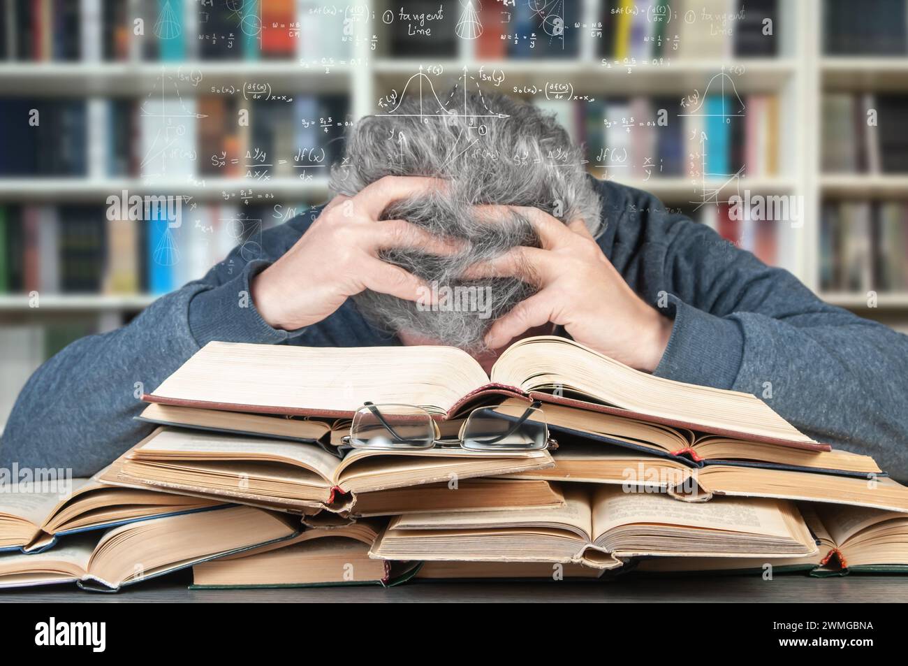 Un adulto cansado de duro estudio yace sobre muchos libros y sueños de fórmulas matemáticas. El concepto de dificultad de aprendizaje en la vejez. Foto de stock