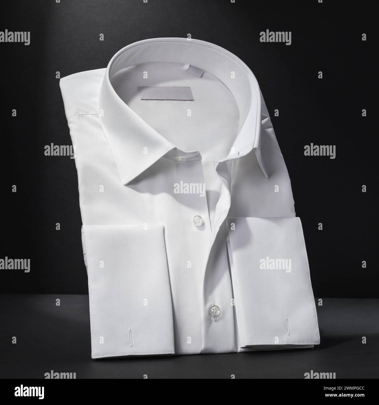 Camisa blanca clásica doblada de manga larga de los hombres sobre un fondo oscuro, primer plano Foto de stock