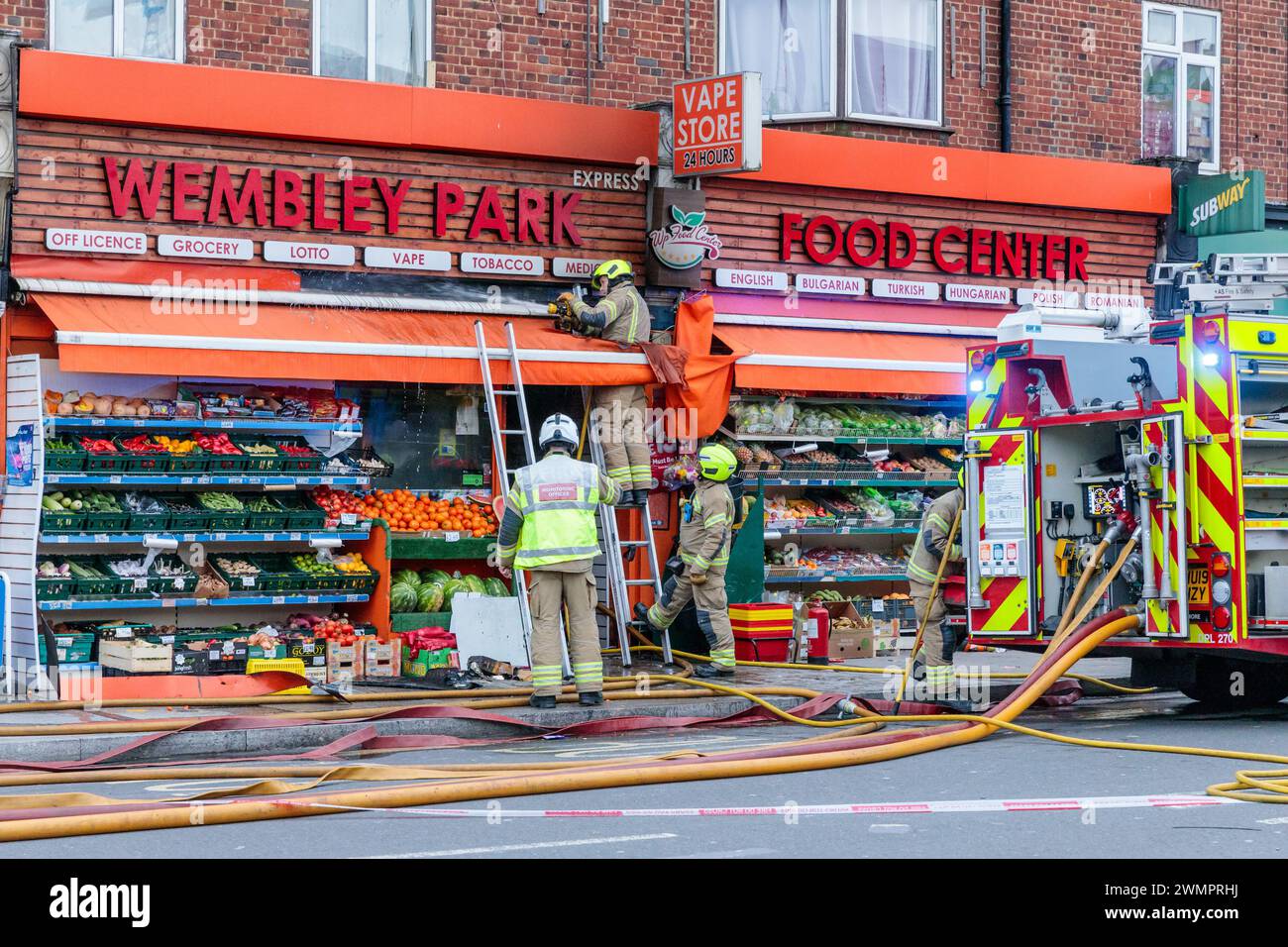 Wembley Park, Reino Unido, 27 de febrero de 2024. Bomberos en la escena de un incendio cerca de la estación de metro Wembley Park, cerrando la calle en ambas direcciones. El incendio en Wembley Park Food Center, Bridge Road, fue reportado por múltiples llamadas a la Brigada de Bomberos alrededor de las 4pm esta tarde. La causa del incendio aún no se conoce, pero se cree que hasta 4 personas están siendo tratadas por quemaduras. Foto de Amanda Rose/Alamy Live News Foto de stock