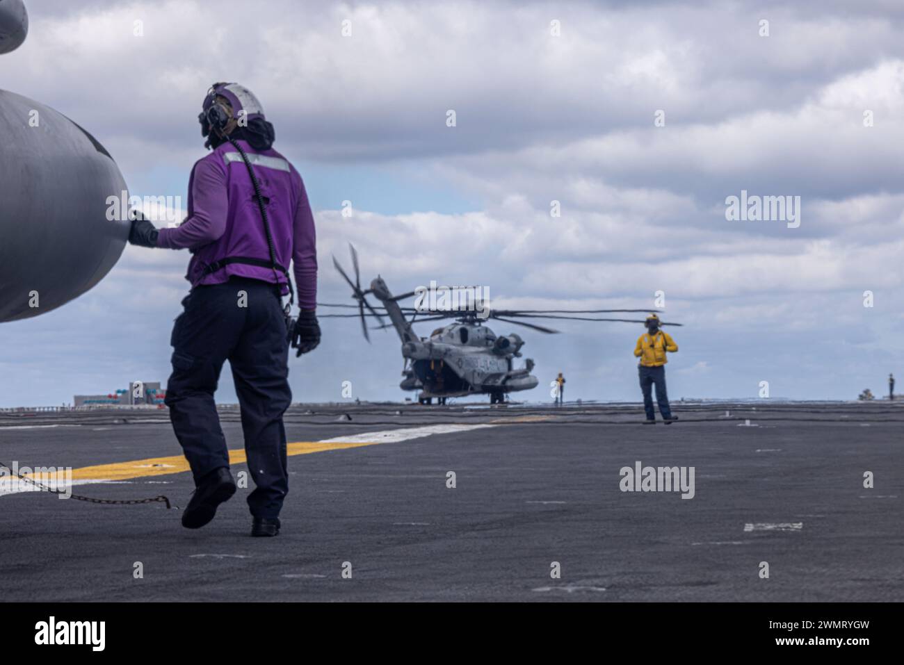 Un marinero de la Marina de los EE.UU. Dirige helicópteros CH-53E Super Stallion con el Escuadrón de Helicópteros Pesados Marinos (HMH) 462, Grupo de Aviones Marítimos 16, 3ª Ala de Aviones de Marina, en la cubierta de vuelo del USS Abraham Lincoln (CVN 72) en el Océano Pacífico, 13 de febrero de 2024. El HMH-462 transportó pasajeros desde la Estación Aérea Naval Isla Norte, Coronado, hasta el Abraham Lincoln, un portaaviones clase Nimitz, y proporcionó apoyo de asalto para operaciones rutinarias en el área de operaciones de la Tercera Flota. Aterrizar en un portaaviones fue una rara oportunidad para los infantes de marina de HMH-462, ya que CH-53E Super Stallions se desplegaron en se Foto de stock
