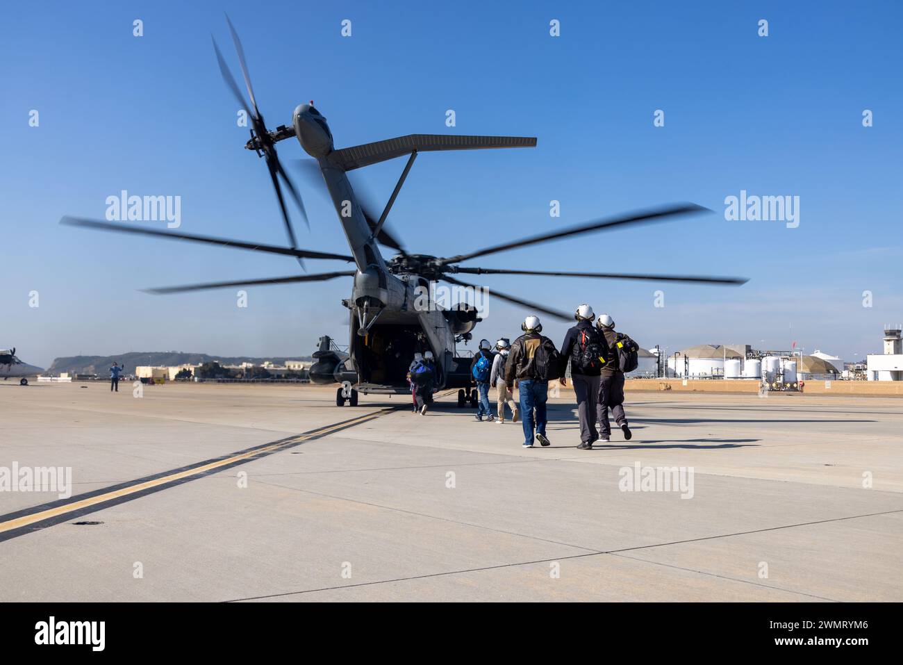 El sargento del Cuerpo de Marines de los Estados Unidos Daniel Hart, jefe de tripulación del CH-53E Super Stallion con el Escuadrón de Helicópteros Pesados Marinos (HMH) 462, Grupo de Aviones Marítimos 16, 3ª Ala de Aviones de Marina, lleva a los pasajeros a los helicópteros en la Estación Aérea Naval Isla Norte, Coronado, California, 13 de febrero de 2024. El HMH-462 transportó pasajeros desde NAS North Island hasta el USS Abraham Lincoln (CVN 72), un portaaviones clase Nimitz, y proporcionó apoyo de asalto para operaciones rutinarias en el área de responsabilidad de la Tercera Flota. Aterrizar en un portaaviones fue una rara oportunidad para los infantes de marina de HMH-462, como CH-53E Super Stal Foto de stock