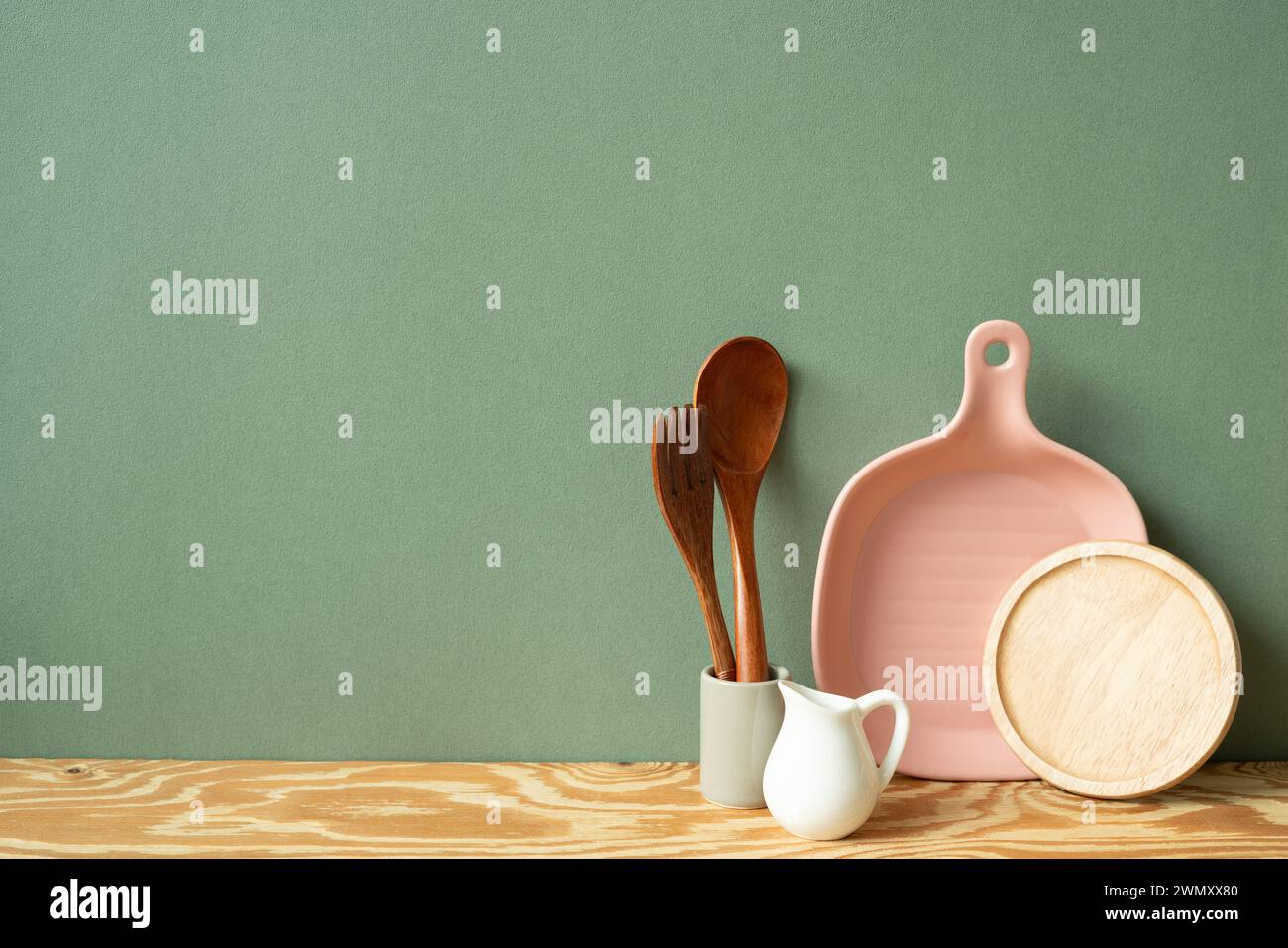 Placa de cerámica de cocina, tostadora, cubertería en estante de madera. fondo de pared verde Foto de stock