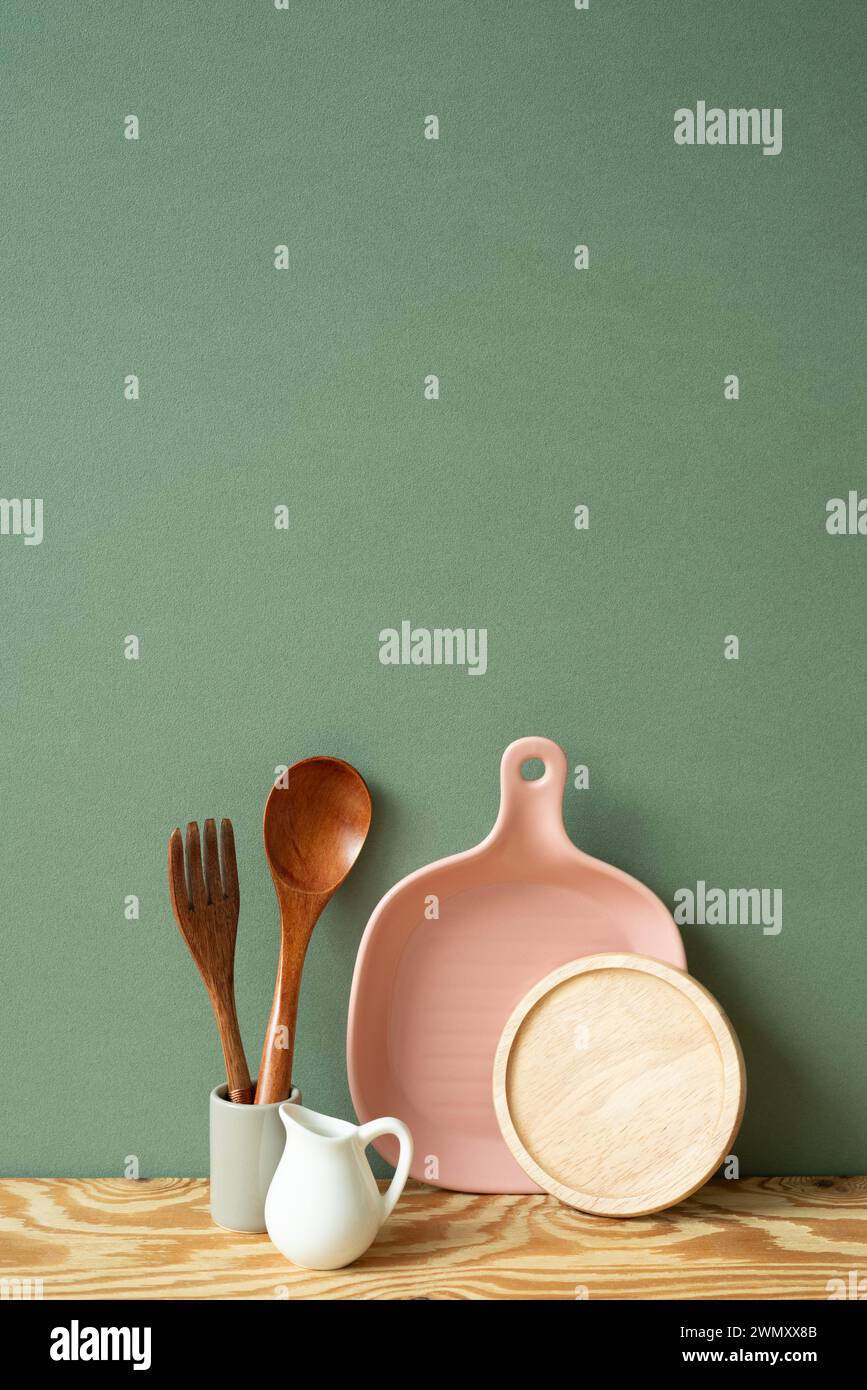 Placa de cerámica de cocina, tostadora, cubertería en estante de madera. fondo de pared verde Foto de stock