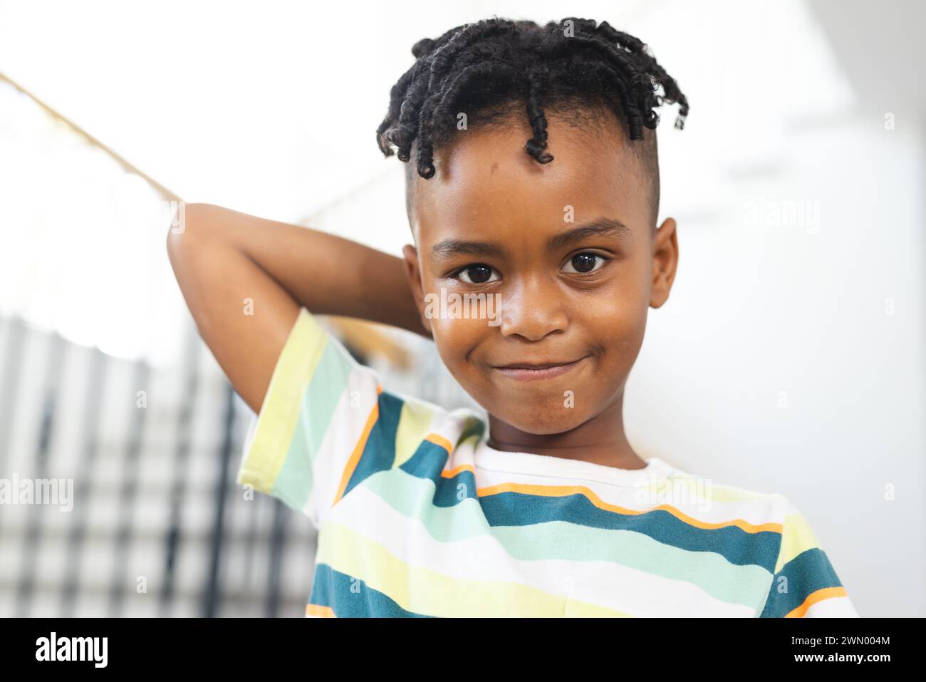 Niño afroamericano con una sonrisa juguetona, con una camisa de rayas Foto de stock