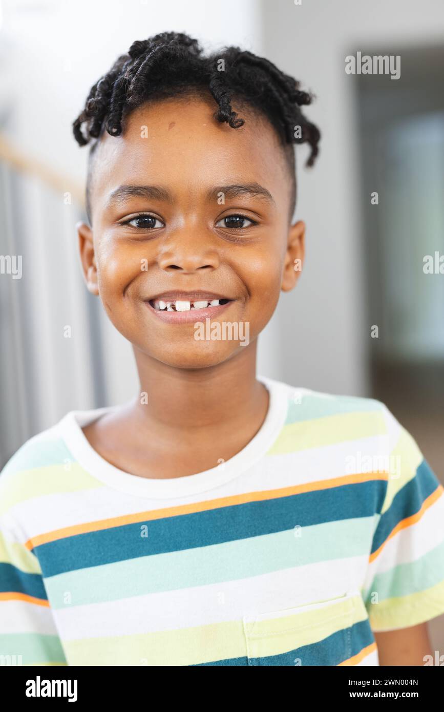 Niño afroamericano con una sonrisa brillante, con una camisa de rayas Foto de stock