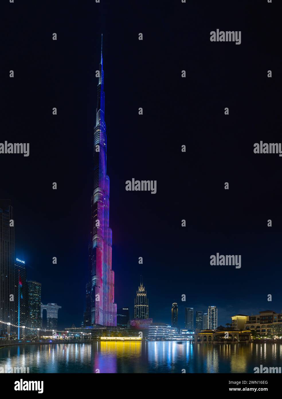 Una imagen del icónico Burj Khalifa con su espectáculo de luces, y los edificios del centro de Dubai y el lago Burj Khalifa, en la noche. Foto de stock