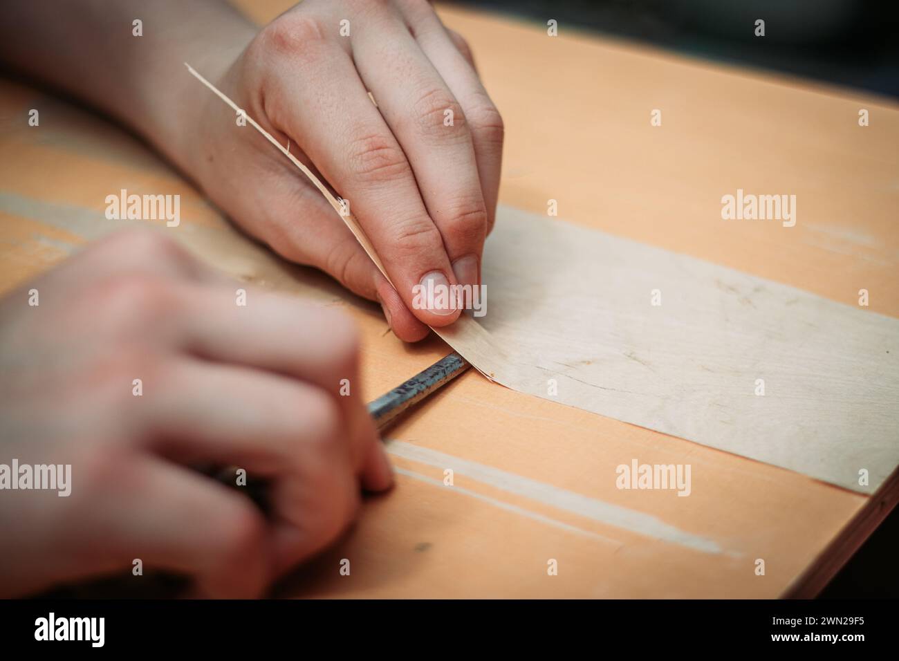 Primer plano de un adolescente usando herramientas que trabajan con sus manos aprendiendo un oficio de carpintería de madera. Foto de stock