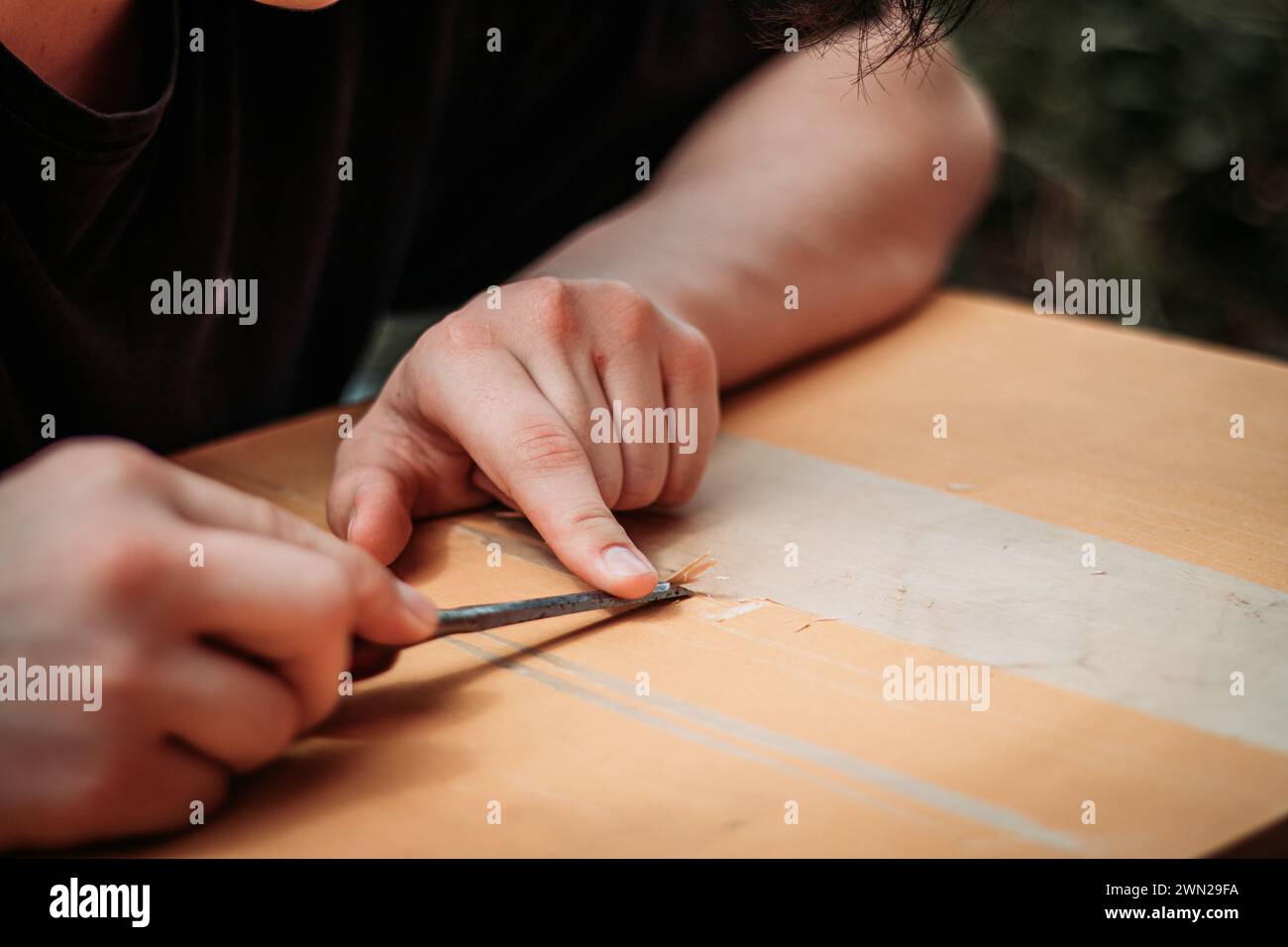 Primer plano de un adolescente usando herramientas que trabajan con sus manos aprendiendo un oficio de carpintería de madera. Foto de stock