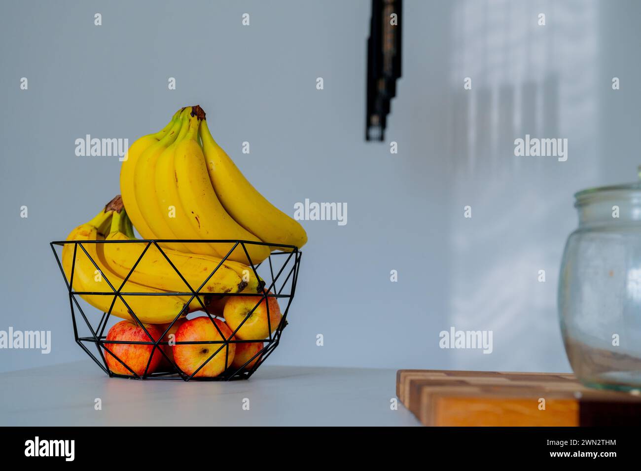 Un tazón de vidrio en el mostrador de la cocina acuna un plátano a la luz del día suave Foto de stock