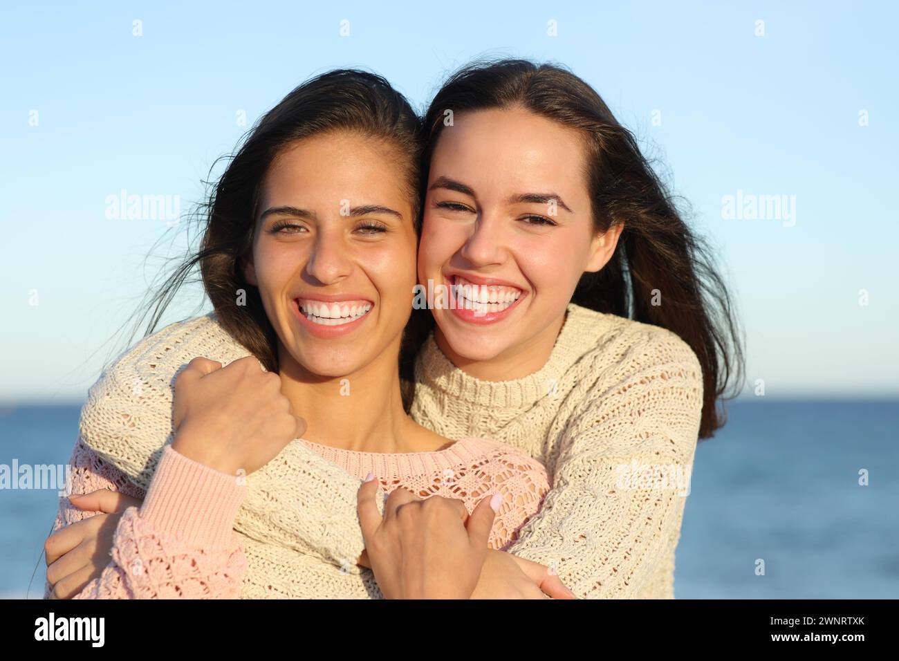 Retrato de vista frontal de dos amigos felices que muestran una sonrisa perfecta en la playa Foto de stock