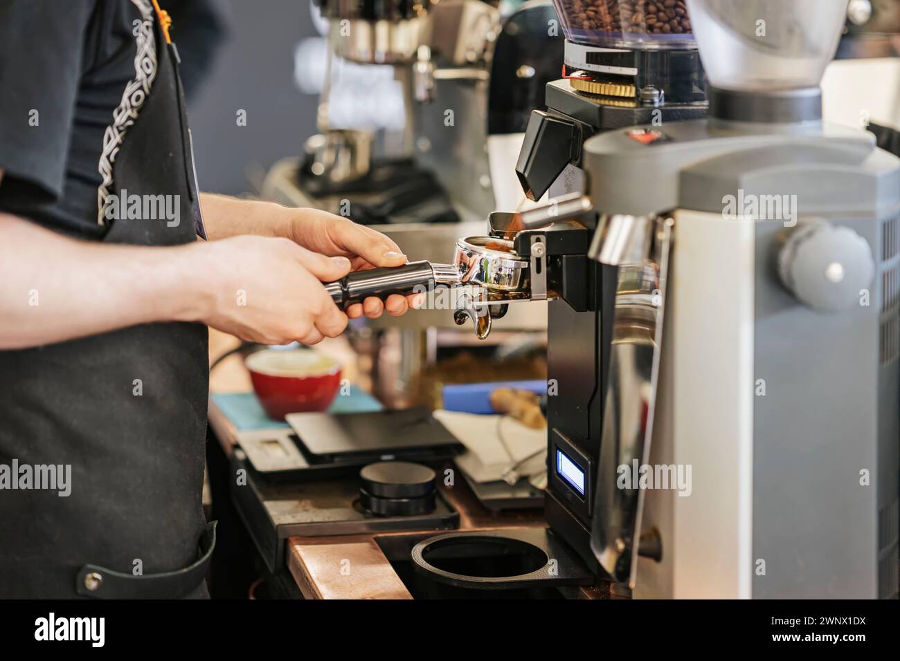 Experto Barista Crafting Espresso Excellence en una cafetería, moliendo café recién tostado en máquina de café espresso. Arte del Café Profesional Pre Foto de stock