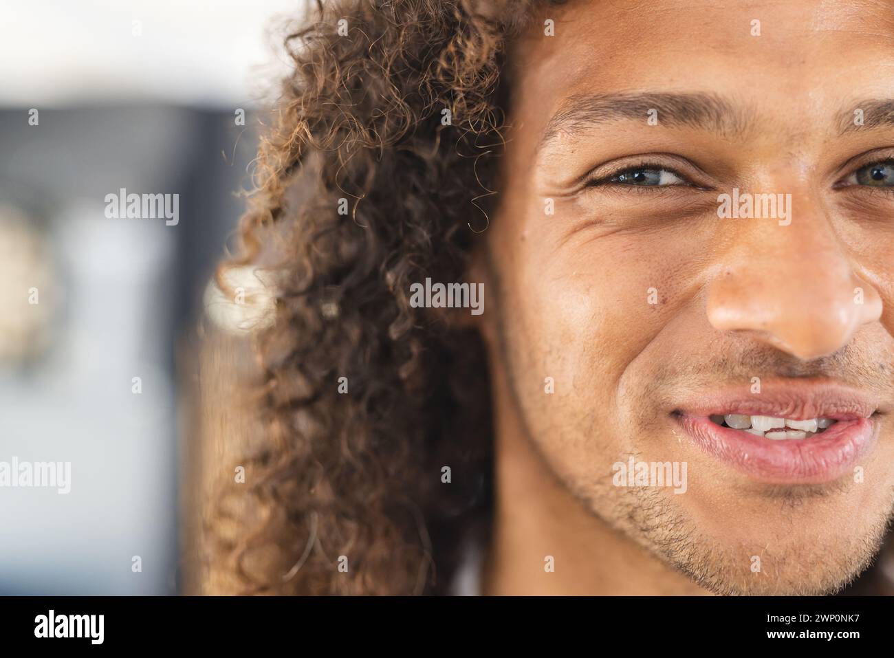Primer plano de un joven biracial con el pelo rizado y una sonrisa cálida Foto de stock