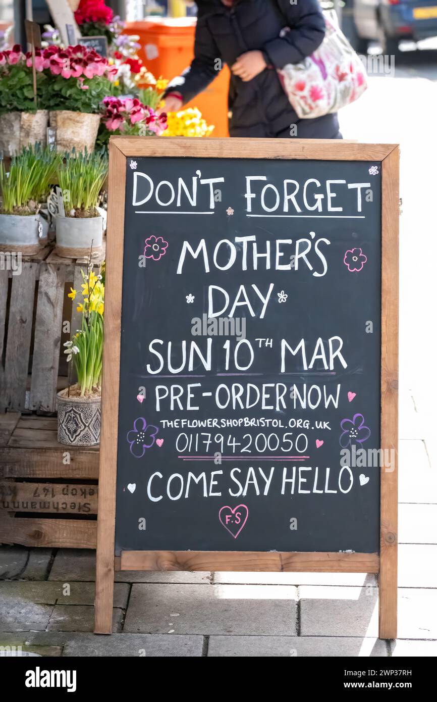 Una exhibición de flores cortadas para la venta fuera de una tienda de floristas con un tablero de sándwich que anuncia el Día de las Madres o el Domingo de Madre se acerca en el Reino Unido Foto de stock