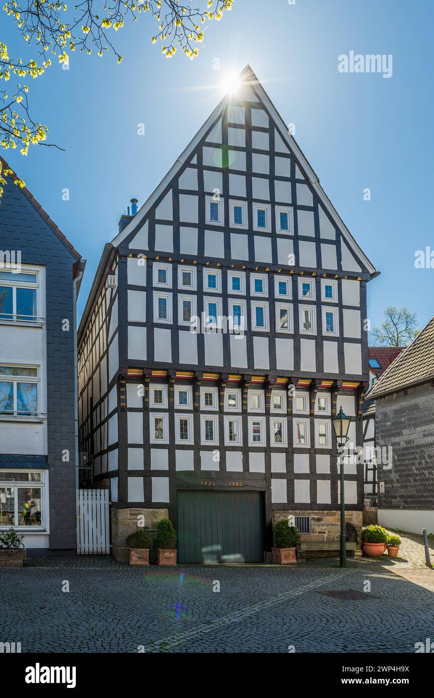 Gran, impresionante casa de entramado de madera bajo un cielo azul brillante con rayos de sol, casco antiguo, Hattingen, distrito de Ennepe-Ruhr, zona de Ruhr, Norte Foto de stock