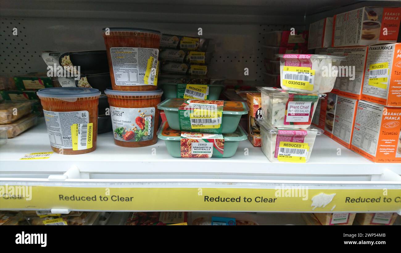 Estante del supermercado con reducir a limpiar los productos alimenticios en el supermercado Tesco, comida de etiqueta amarilla Foto de stock