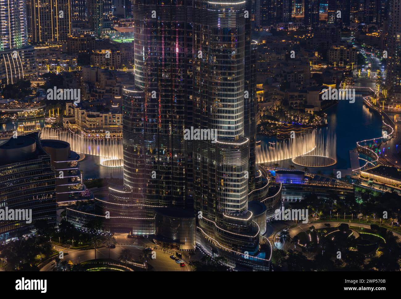 Una foto del Dubai Fountain Show, por la noche, y la parte inferior del Burj Khalifa, junto a otros edificios del centro de Dubai. Foto de stock