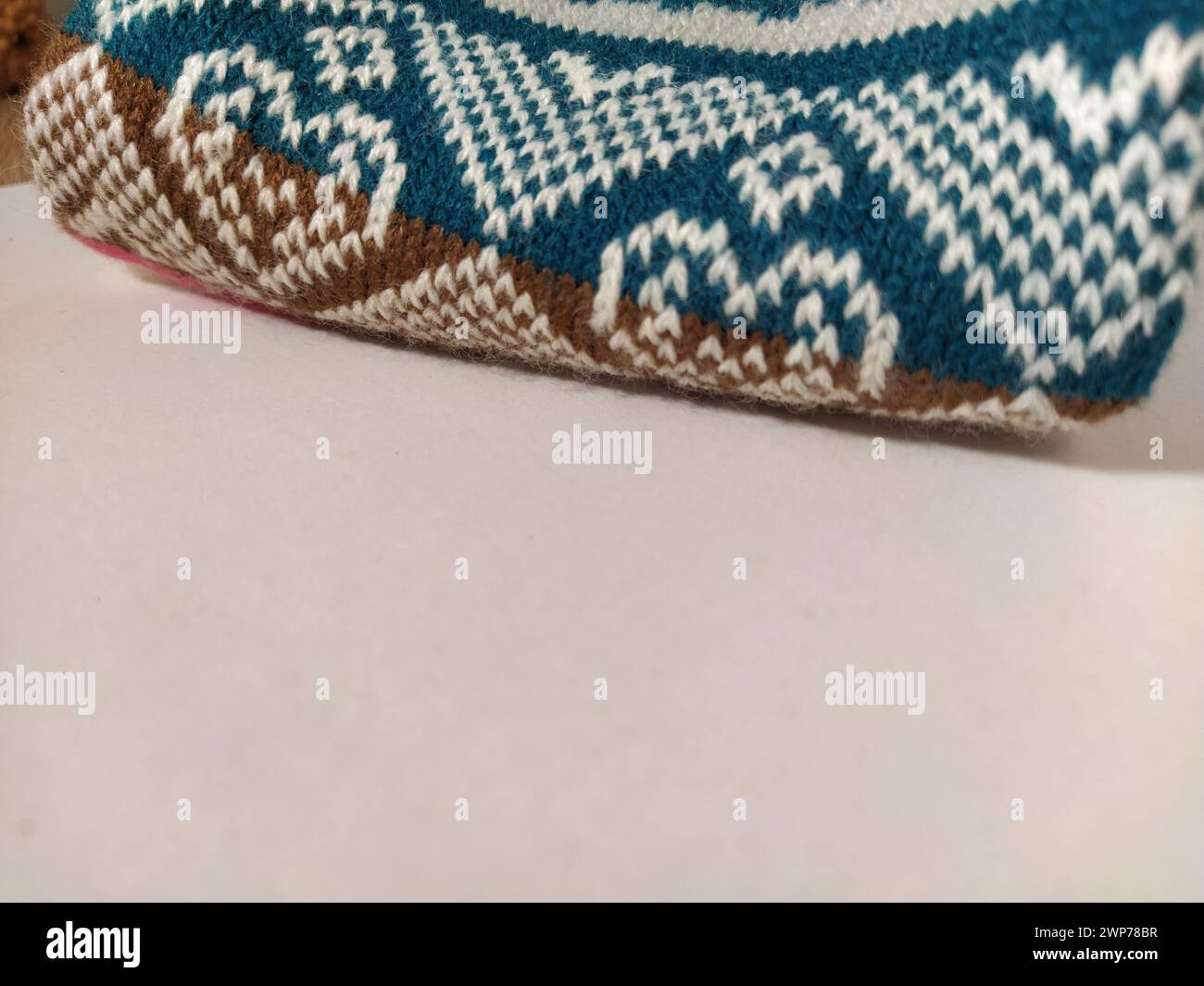 Un fragmento de un adorno en un suéter de poliéster o lana de punto. Motivos de invierno. Rombos, líneas rotas, olas. Patrón de punto de blanco, rosa, Foto de stock