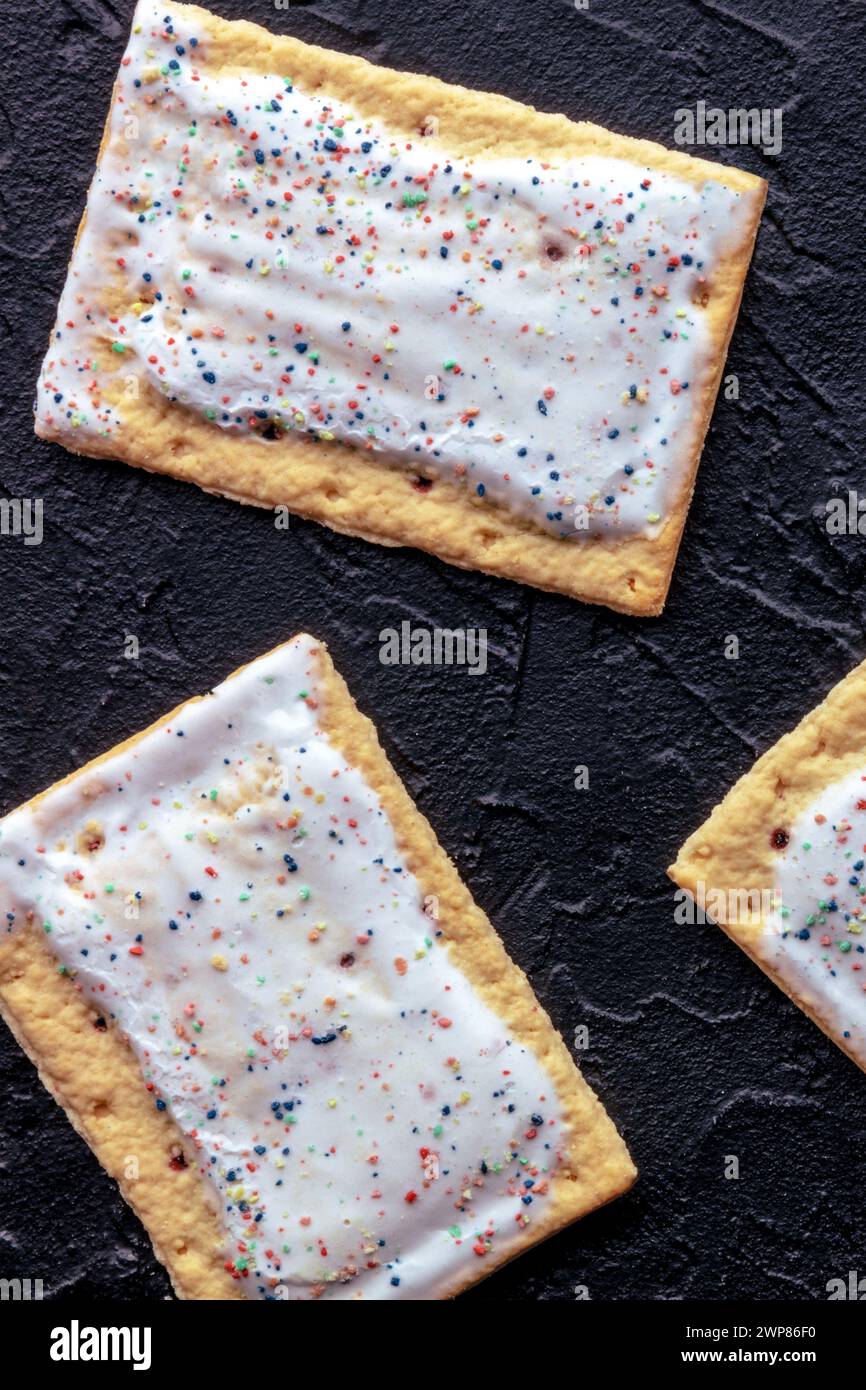 POP tartas en negro. Poptart tostadora de pastelería con hielo, tiro desde arriba, comida de desayuno Foto de stock