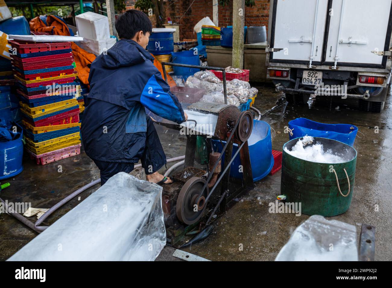 Trabajador con bloques de hielo en el mercado de pescado de Hoi An Foto de stock