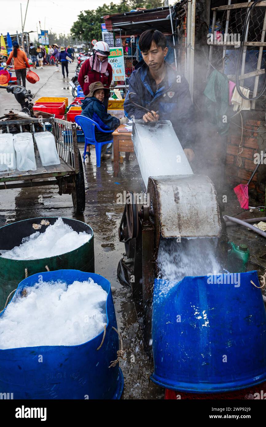 Trabajador con bloques de hielo en el mercado de pescado de Hoi An Foto de stock