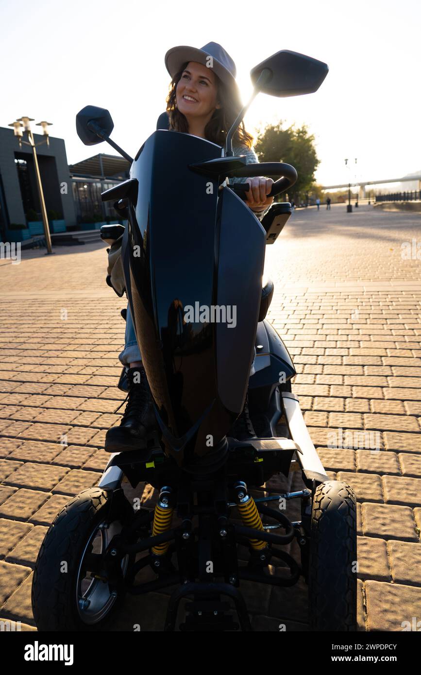 Mujer turista montando un scooter eléctrico de movilidad de cuatro ruedas en una calle de la ciudad.. Foto de stock