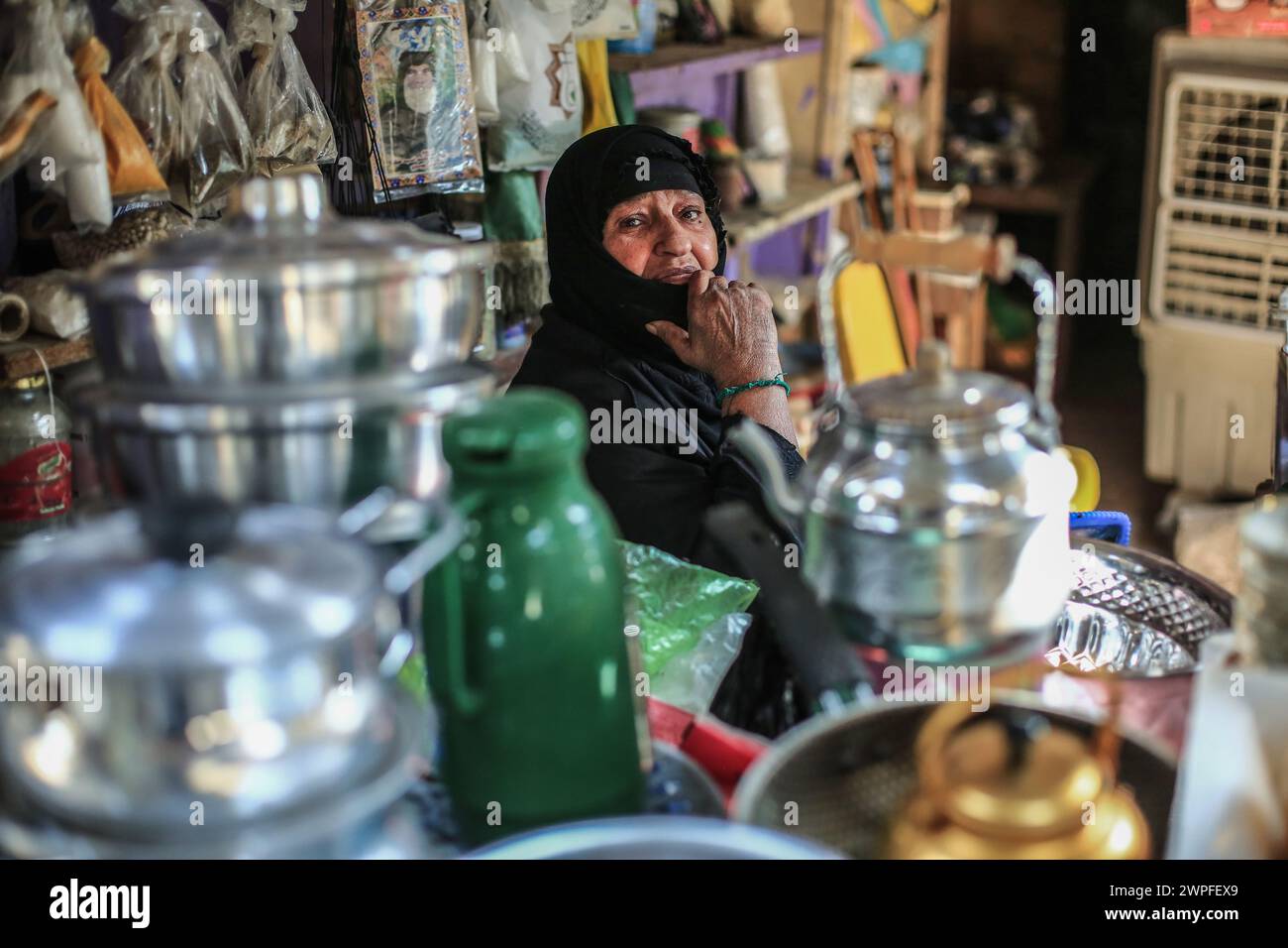 Bagdad, Irak. 07 de marzo de 2024. Umm Mushtaq, de 70 años, trabaja en el campo de la venta de suministros para el hogar. Ella practica este trabajo con su esposo e hijos porque solían poseer una fábrica para hacer utensilios y suministros para el hogar. La fábrica se cerró debido a la falta de materias primas para la industria, lo que les obligó a abrir esta tienda en el mercado de Sadr City. Ella es el único sostén de la familia, incluyendo a sus nietos después de que su esposo murió y su hijo murió en un accidente de tráfico. Crédito: Ameer Al-Mohammedawi/dpa/Alamy Live News Foto de stock