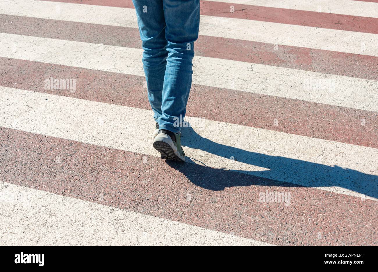 mujer en jeans caminando a través de un cruce peatonal, de cerca Foto de stock