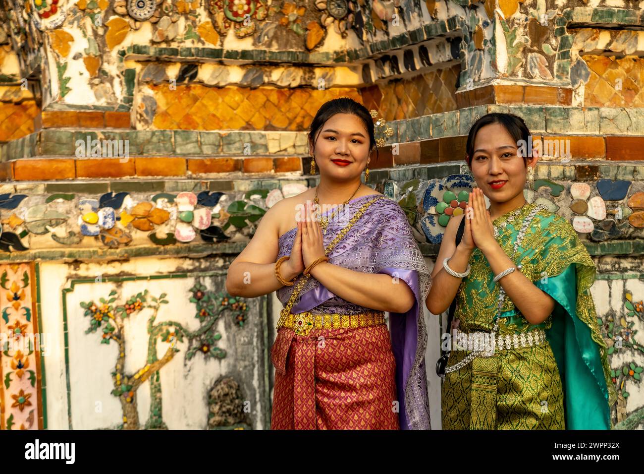 Mujeres tradicionalmente vestidas posan frente al templo Wat Arun o Templo del Amanecer en Bangkok, Tailandia, Asia Foto de stock