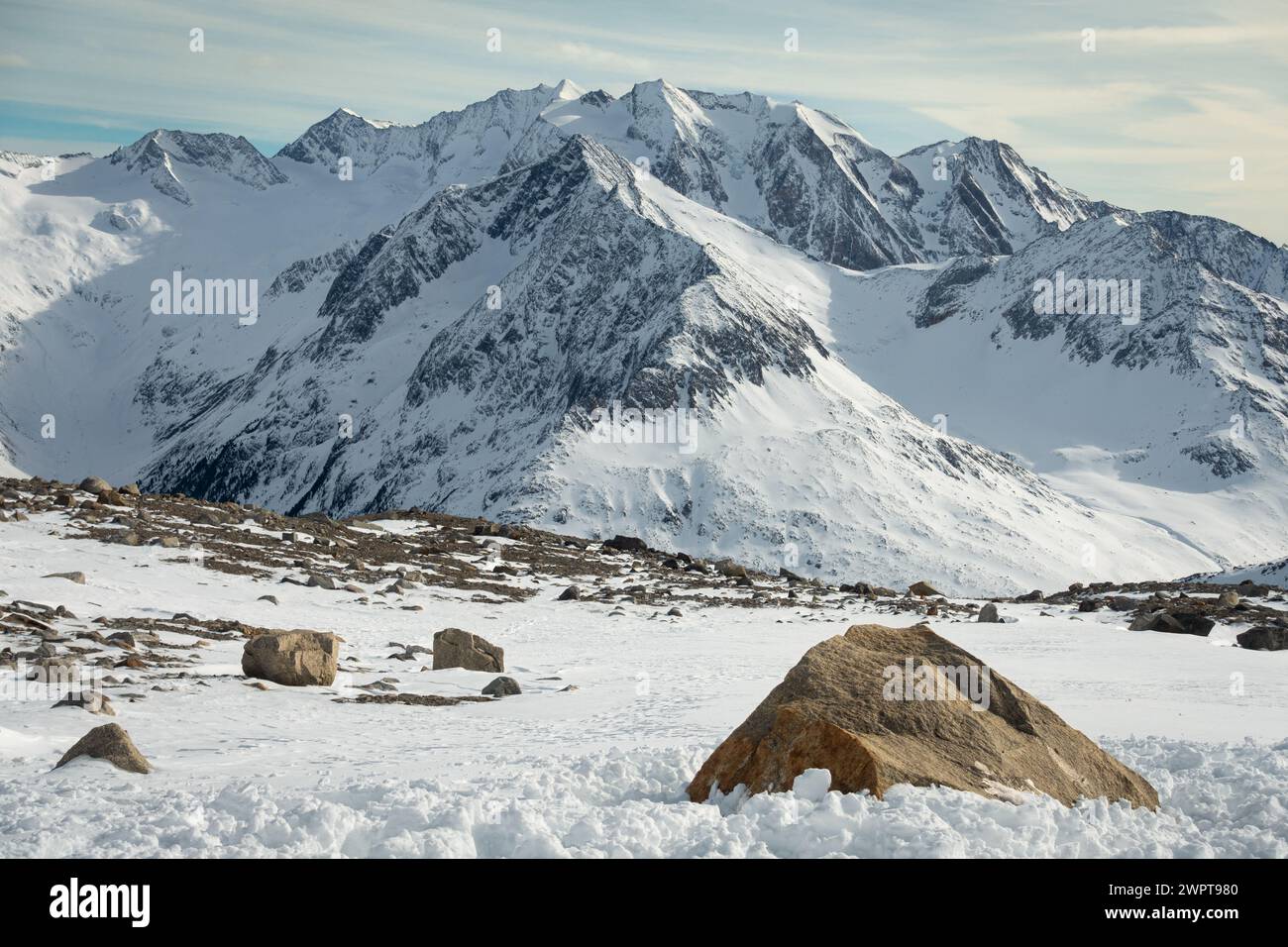 Paisaje alpino con rocas amarillas en la parte delantera y picos cubiertos de nieve y nubes, hermosos colores en la cima de un glaciar, Hintertux, Austria Foto de stock