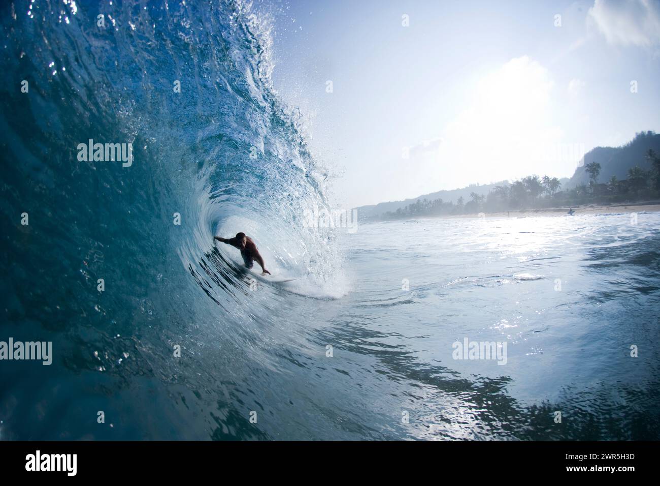 Vista desde el agua de un joven surfeando en el tubo en Rocky Point en Hawai. Foto de stock