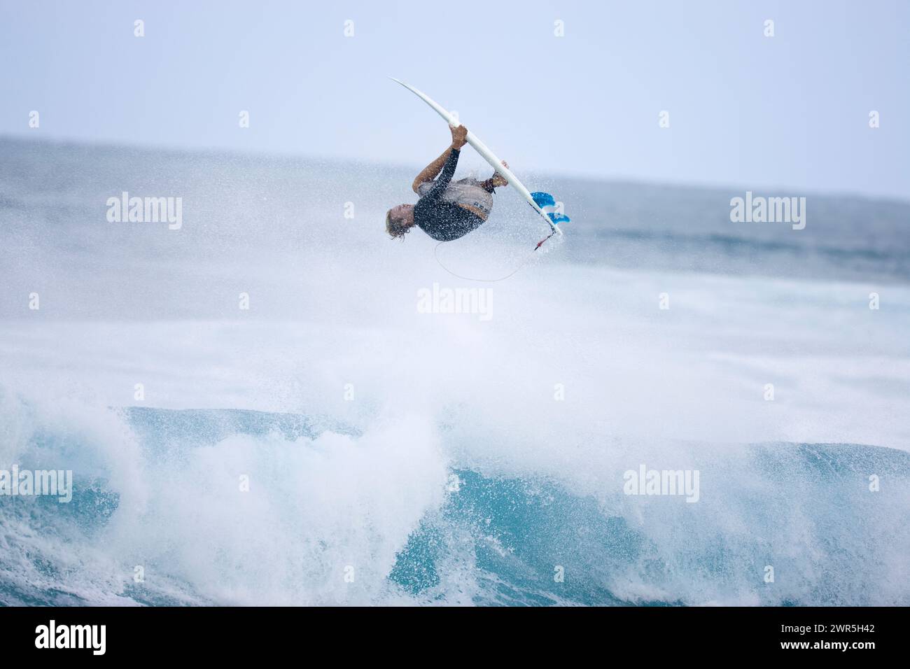 Un joven que realiza una maniobra vertical mientras navega en Rocky Point en la costa norte de Oahu, Hawai. Foto de stock