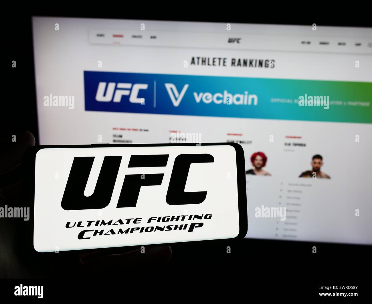 Persona que sostiene el smartphone con el logotipo de la compañía de artes marciales Ultimate Fighting Championship (UFC) delante del sitio web. Enfoque en la pantalla del teléfono. Foto de stock