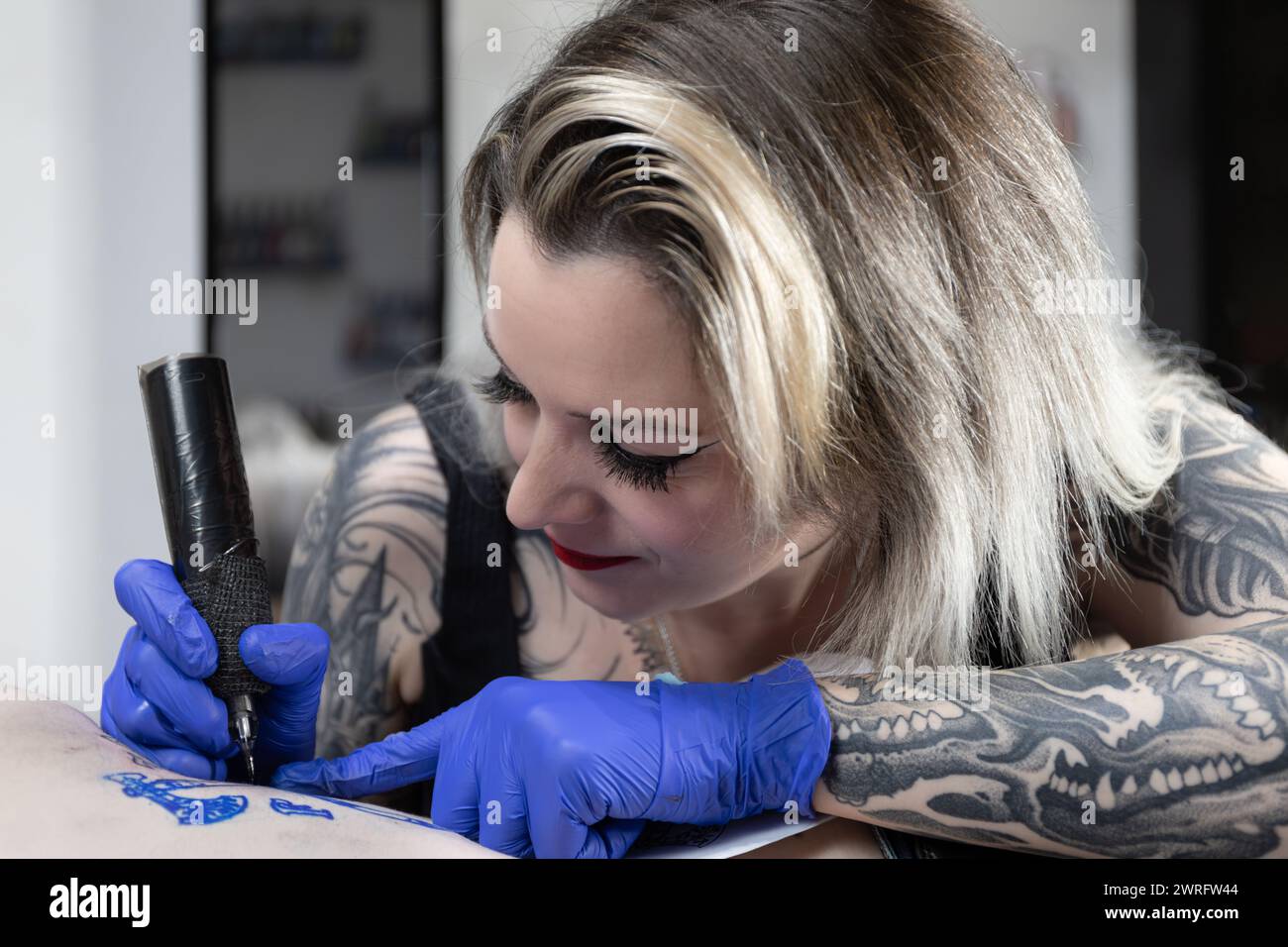 Foto horizontal Con una expresión serena, una artista del tatuaje está completamente inmersa en entintar un diseño complejo, mostrando su talento innato y su mano firme. Foto de stock