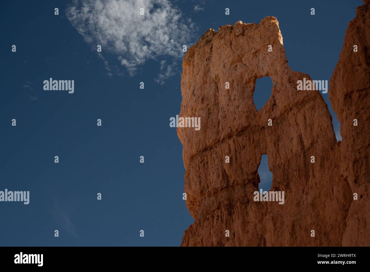 Dos agujeros se forman en Narrow Hoodoo para mostrar el cielo azul en Bryce Canyon Foto de stock