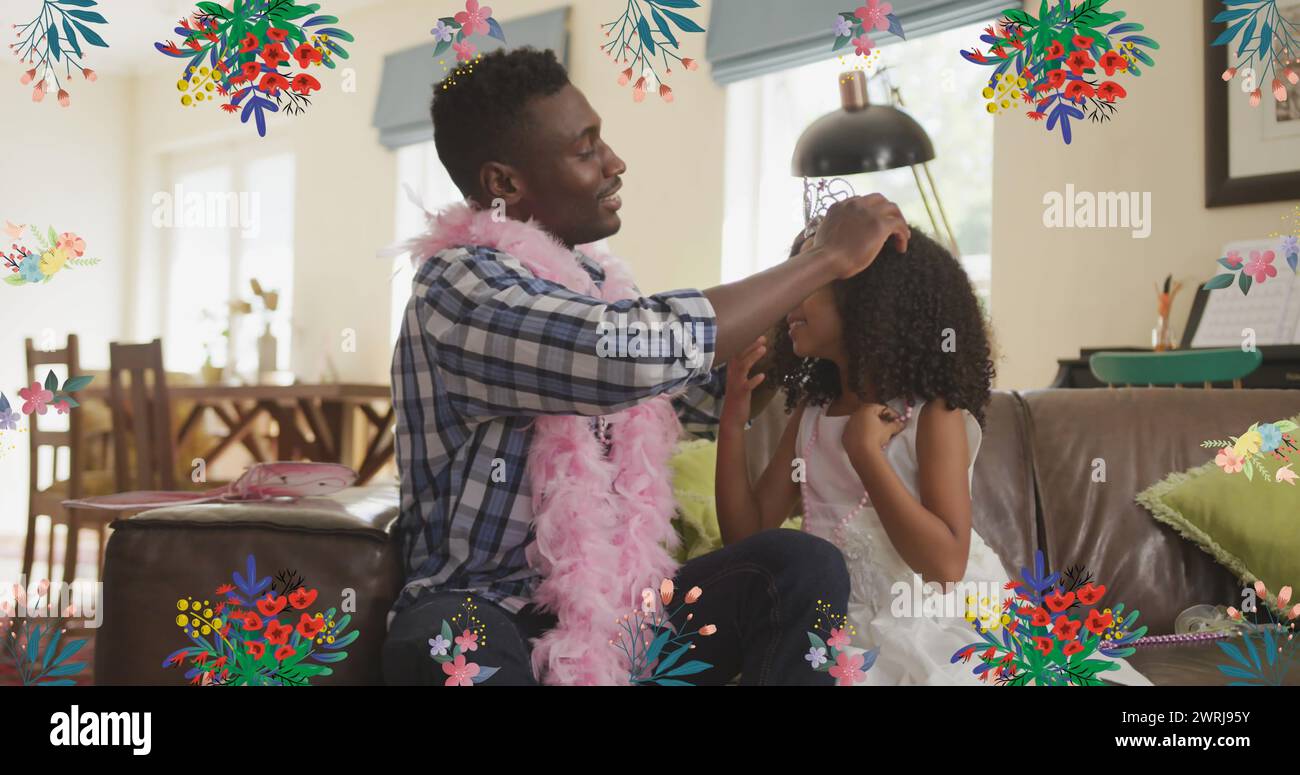 Imagen de flores sobre padre afroamericano feliz poniendo corona a hija en casa Foto de stock