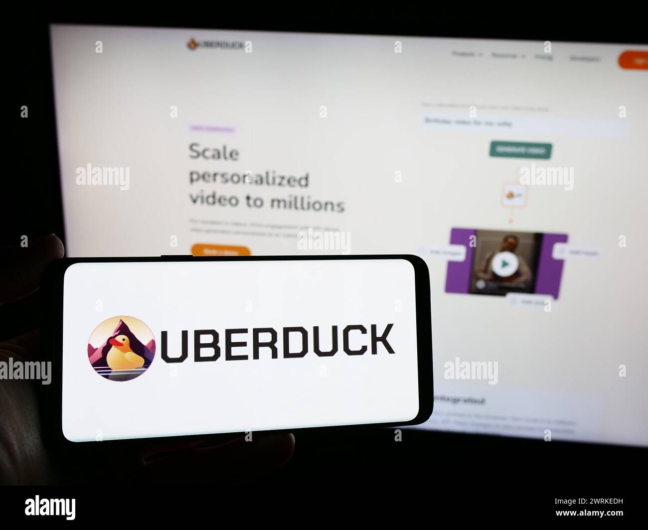 Persona que sostiene el smartphone con el logotipo de la compañía estadounidense de música de inteligencia artificial Uberduck Inc. Frente al sitio web. Enfoque en la pantalla del teléfono. Foto de stock