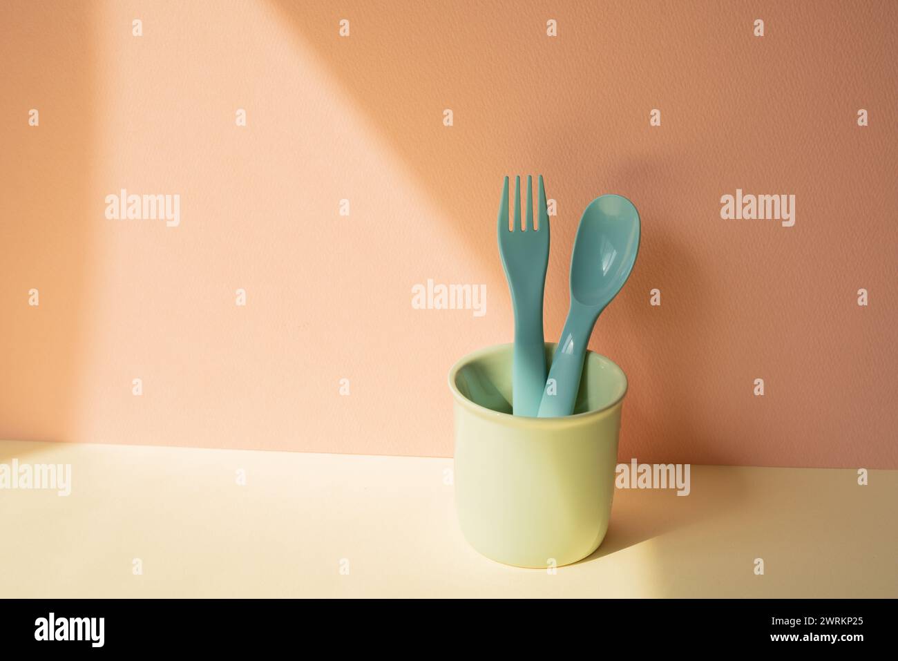 Cocina azul cubertería tenedor y cuchara en el sostenedor en la mesa de marfil. fondo de pared rosa Foto de stock