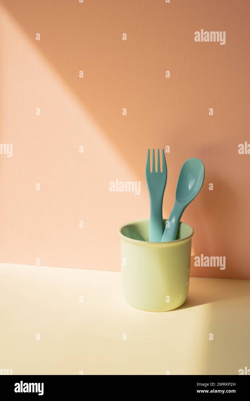 Cocina azul cubertería tenedor y cuchara en el sostenedor en la mesa de marfil. fondo de pared rosa Foto de stock