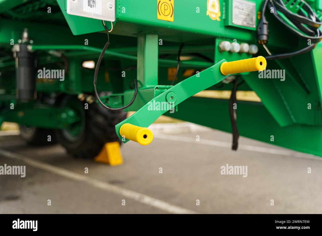 Una visión de cerca de una parte de los equipos agrícolas verdes con conectores hidráulicos, centrándose en la precisión y la tecnología en la agricultura moderna. Foto de stock