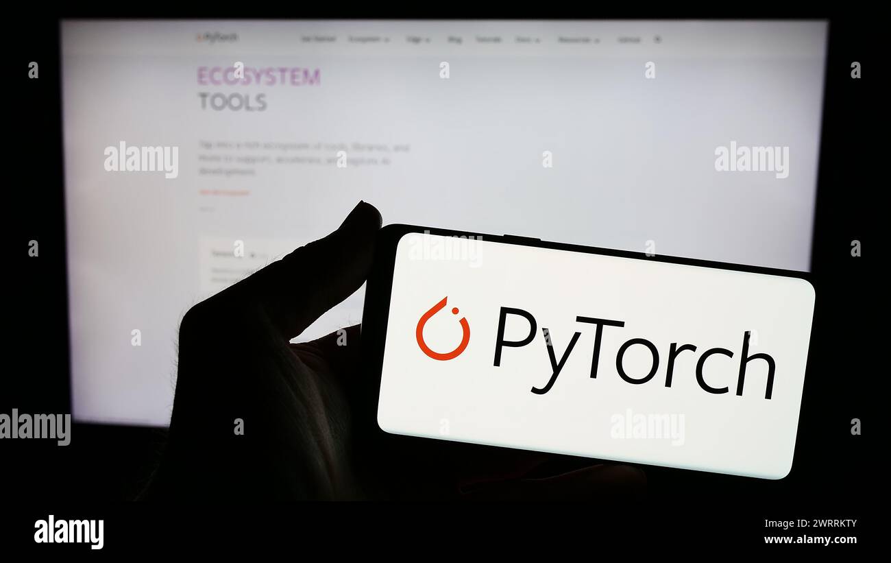 Persona que sostiene el smartphone con el logotipo de la biblioteca de aprendizaje automático PyTorch en frente del sitio web. Enfoque en la pantalla del teléfono. Foto de stock