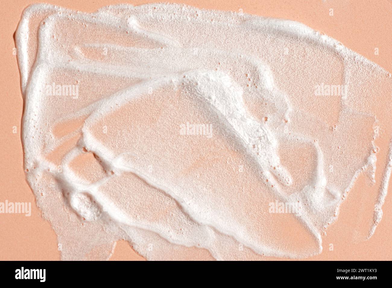 Muestra de mousse de limpieza facial. Burbujas blancas de espuma limpiadora sobre fondo beige rosa. Jabón, gel de ducha, champú espuma textura de primer plano. Foto de stock