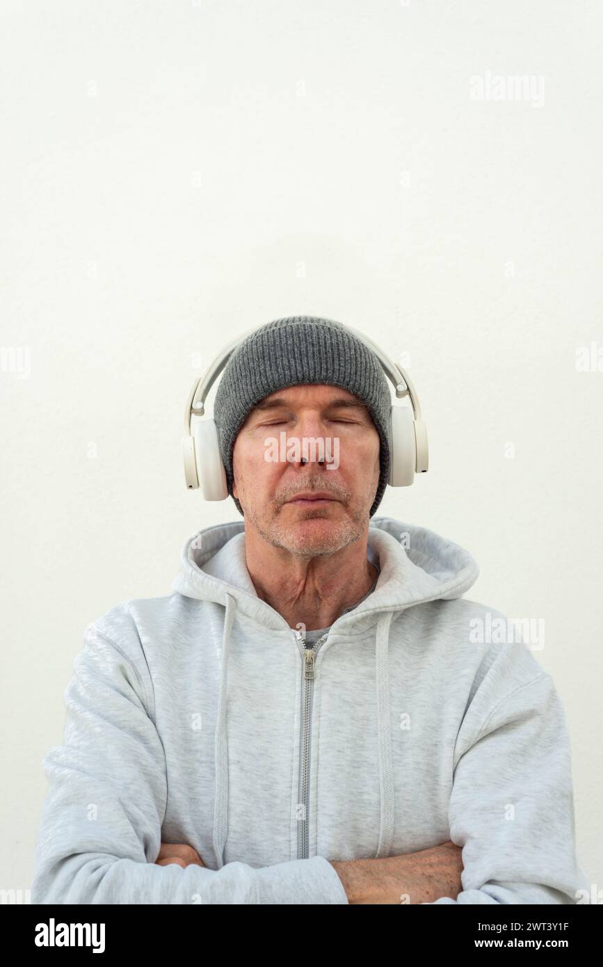 Hombre con auriculares con los ojos cerrados escuchando música. Foto de stock
