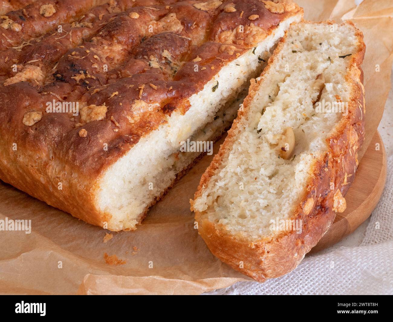 Caliente pan recién horneado con queso y ajo, enfoque selectivo. Pan rústico de masa madre y una rebanada cortada Foto de stock