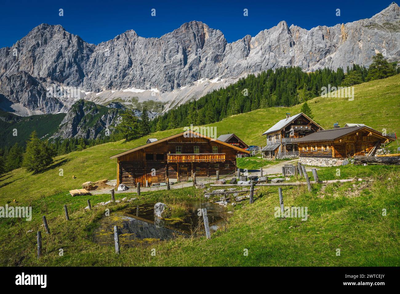 Admirable paisaje alpino, casas de madera en la ladera y pintorescas montañas altas en el fondo, grupo de montaña Dachstein, Ramsau am Dachstein Foto de stock