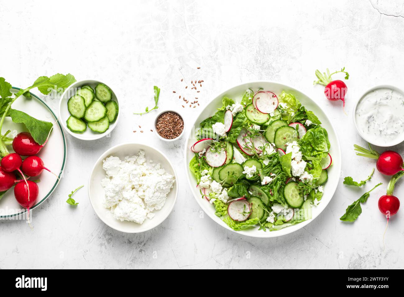 Rábano y pepino Ensalada fresca de verduras de hoja verde con lechuga romana, queso cottage y yogur, vista superior Foto de stock