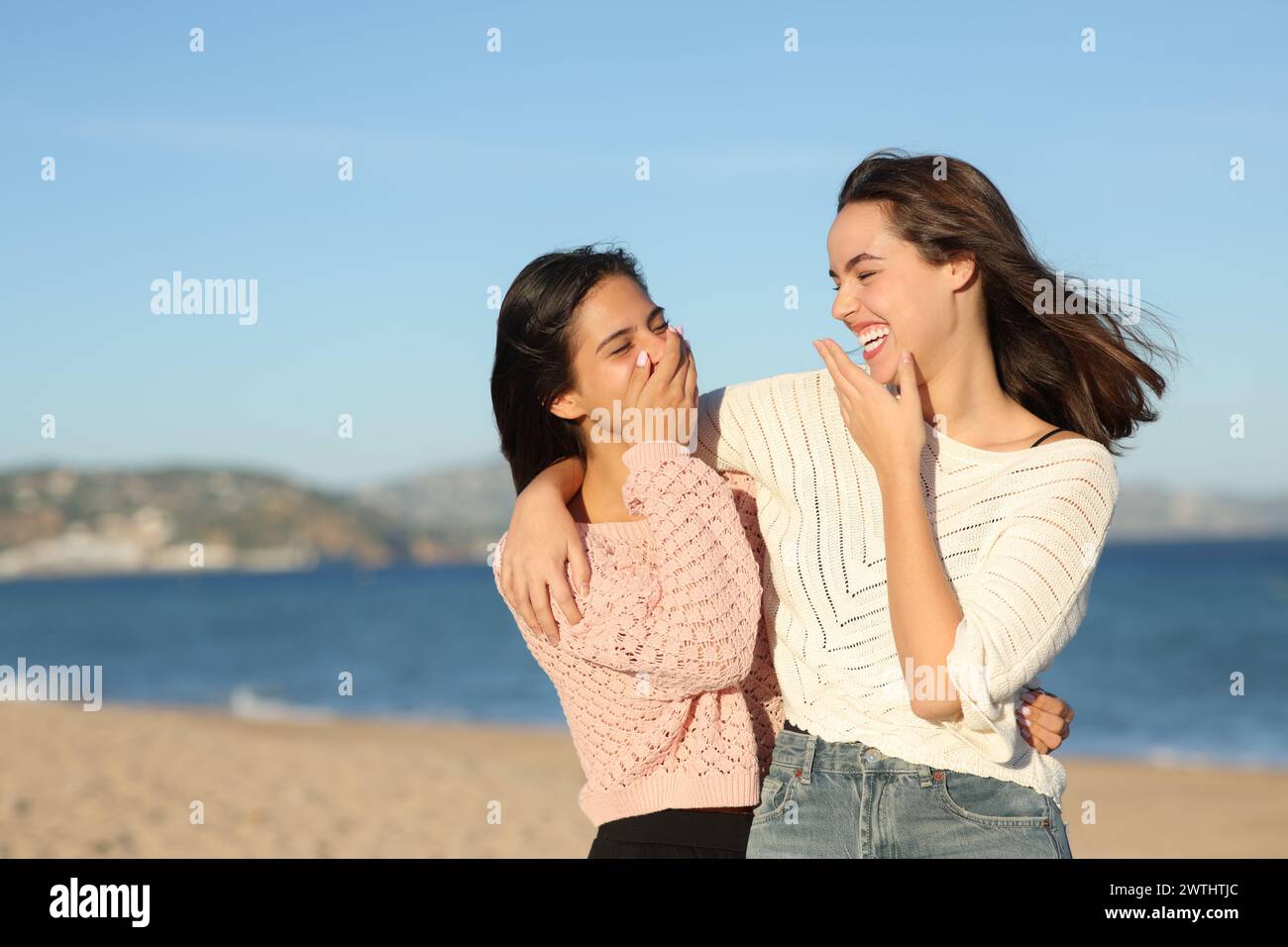 Mejores amigos felices hablando y riendo caminando en la playa Foto de stock